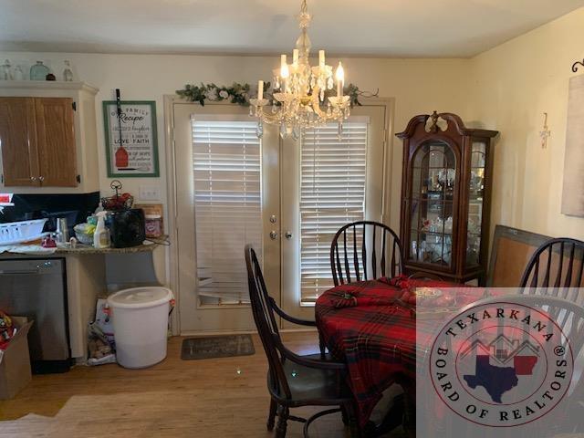 dining space featuring light wood-type flooring, french doors, and an inviting chandelier