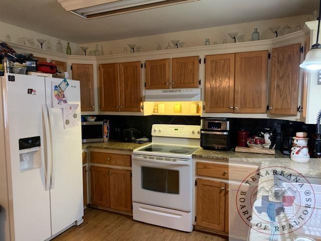 kitchen featuring white appliances, light hardwood / wood-style floors, and decorative backsplash