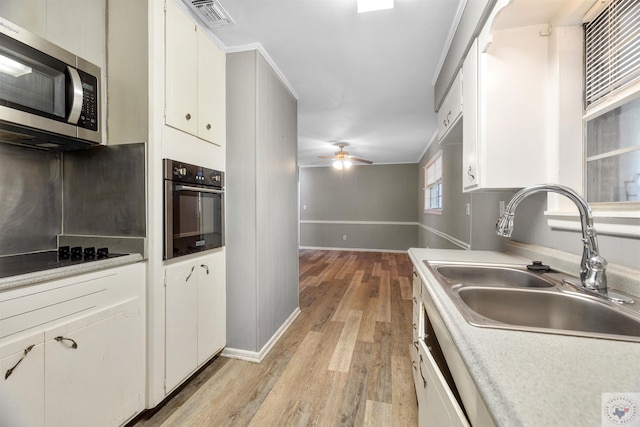 kitchen with crown molding, ceiling fan, sink, white cabinets, and stainless steel appliances