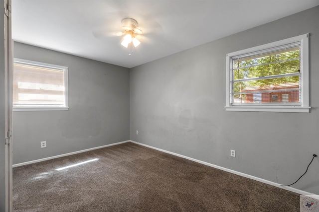 empty room with dark colored carpet and ceiling fan