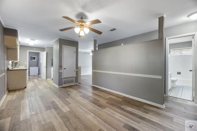 unfurnished living room with ceiling fan, sink, and light wood-type flooring