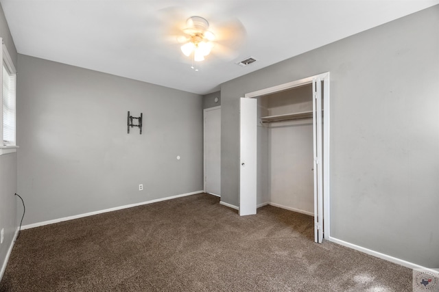 unfurnished bedroom with ceiling fan, a closet, and dark colored carpet