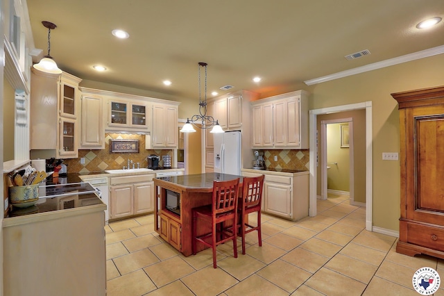 142 Easy St, Texarkana, TX 75503 - kitchen featuring white fridge with ice dispenser, decorative backsplash, light tile patterned flooring, a center island, and dark countertops