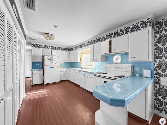 3223 Walnut St, Texarkana, TX 75503 - kitchen with white appliances, dark wood-style flooring, a peninsula, tasteful backsplash, and white cabinetry