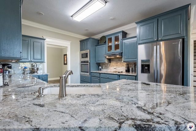 kitchen featuring light stone countertops, a sink, stainless steel appliances, backsplash, and ornamental molding