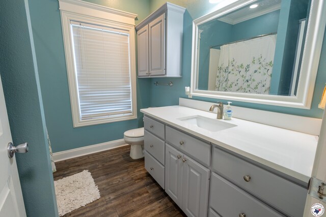 bathroom with crown molding, vanity, toilet, baseboards, and wood finished floors