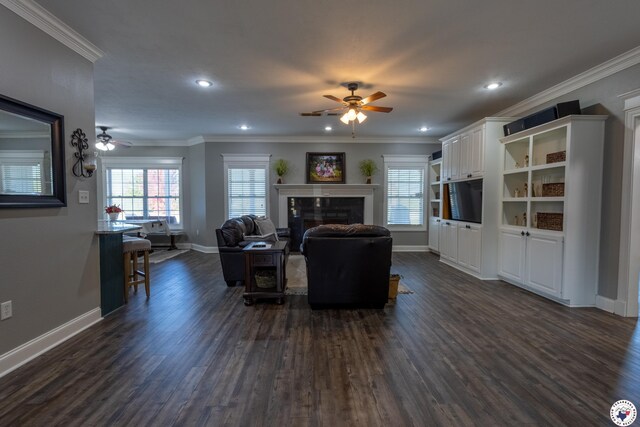 living room featuring a ceiling fan, crown molding, a fireplace, baseboards, and dark wood-type flooring
