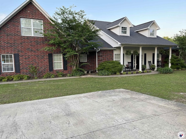view of front of property with covered porch, brick siding, and a front lawn