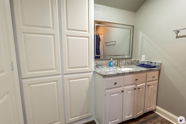 bathroom with baseboards, wood finished floors, and vanity