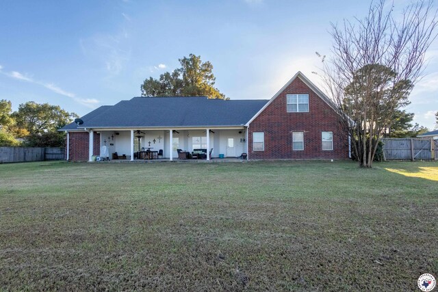 view of front of house with a fenced backyard, ceiling fan, a front yard, and brick siding