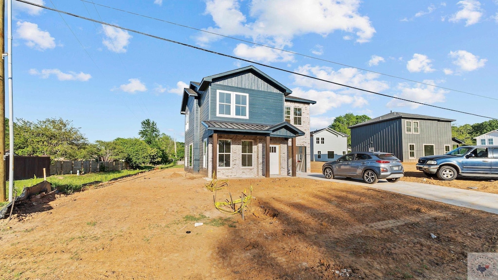 traditional home featuring fence, driveway, and metal roof