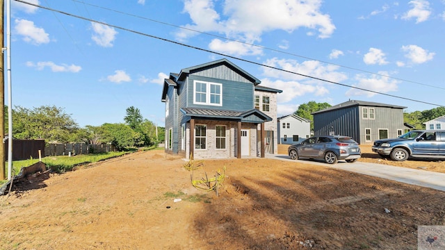 traditional home featuring fence, driveway, and metal roof
