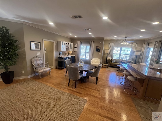 dining room featuring light wood-type flooring, visible vents, and crown molding