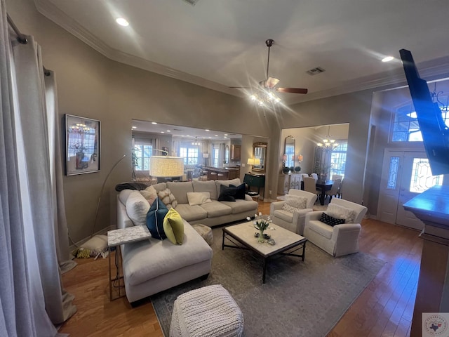 living room with ornamental molding, visible vents, a towering ceiling, and wood finished floors