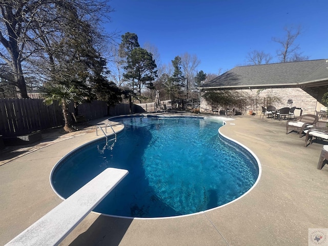 view of pool with a fenced backyard, a diving board, a fenced in pool, and a patio