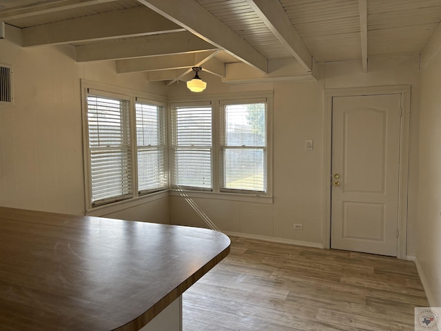 unfurnished dining area featuring light hardwood / wood-style flooring and beam ceiling