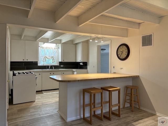 kitchen featuring kitchen peninsula, light hardwood / wood-style floors, white cabinetry, and white range with gas stovetop