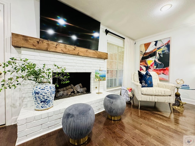 living area with crown molding, hardwood / wood-style floors, a textured ceiling, and a brick fireplace