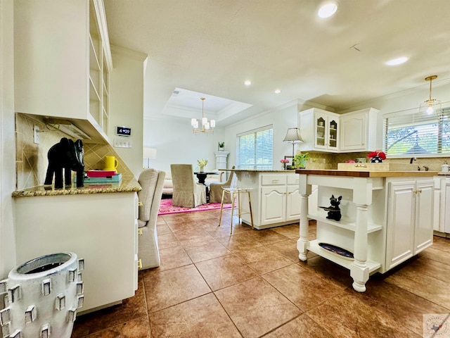 kitchen with decorative backsplash, pendant lighting, white cabinets, and a kitchen island