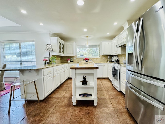 kitchen featuring white appliances, decorative backsplash, white cabinets, a kitchen island, and decorative light fixtures