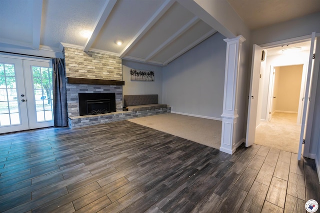 unfurnished living room with dark wood-style flooring, lofted ceiling with beams, a fireplace, french doors, and ornate columns
