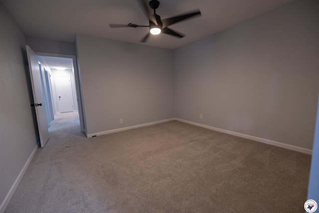 carpeted spare room featuring baseboards and a ceiling fan