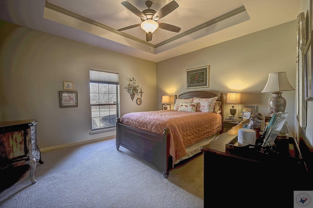 carpeted bedroom with ceiling fan and a tray ceiling