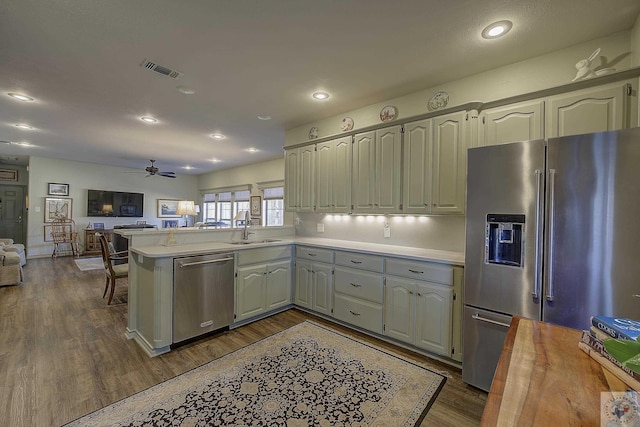 kitchen with dark wood-type flooring, sink, kitchen peninsula, and stainless steel appliances