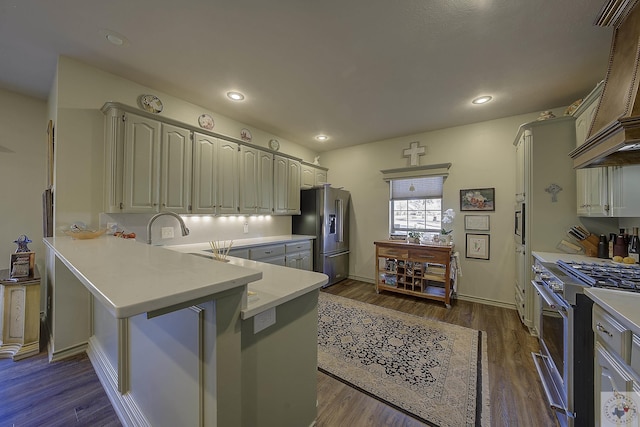 kitchen featuring premium range hood, high end appliances, sink, kitchen peninsula, and dark hardwood / wood-style floors