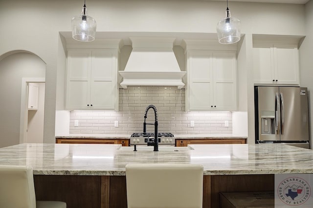 kitchen featuring white cabinetry, light stone countertops, stainless steel fridge with ice dispenser, and custom exhaust hood