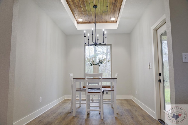 unfurnished dining area featuring hardwood / wood-style flooring, wood ceiling, a chandelier, and a tray ceiling