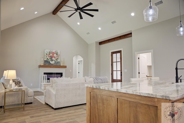 living room with sink, high vaulted ceiling, light wood-type flooring, beamed ceiling, and ceiling fan