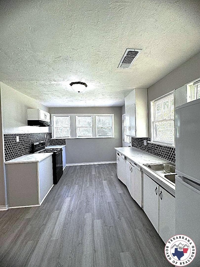 kitchen featuring visible vents, black electric range oven, dark wood finished floors, white cabinets, and freestanding refrigerator