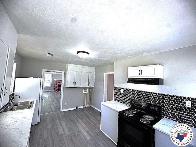 kitchen with black electric range oven, dark wood finished floors, a sink, light countertops, and white cabinetry