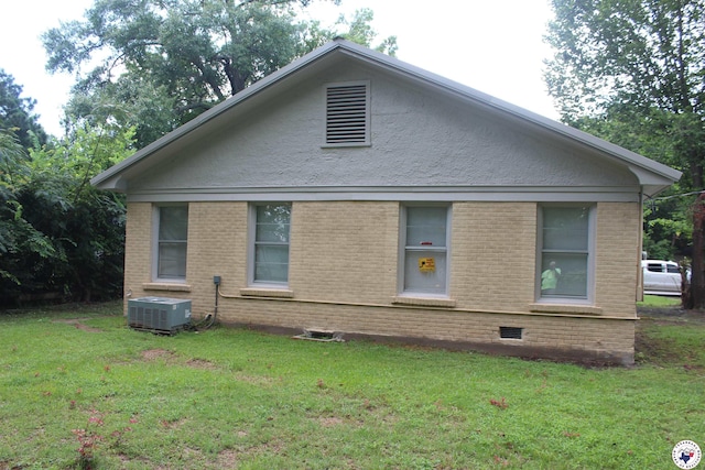 view of side of property featuring a yard, brick siding, and cooling unit