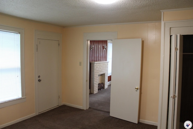 foyer entrance with crown molding, dark carpet, and a textured ceiling