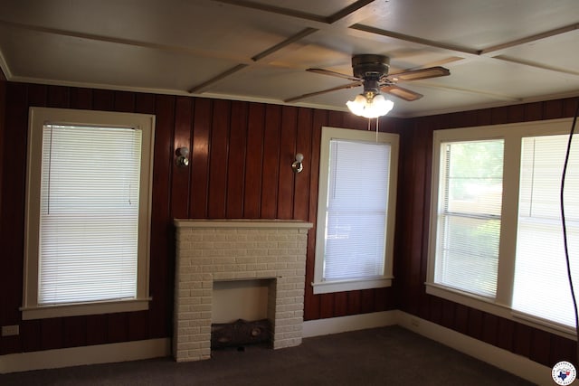 unfurnished living room featuring carpet floors, wood walls, a brick fireplace, and ceiling fan