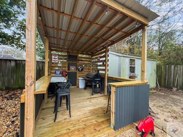 deck with exterior bar, a storage shed, and grilling area