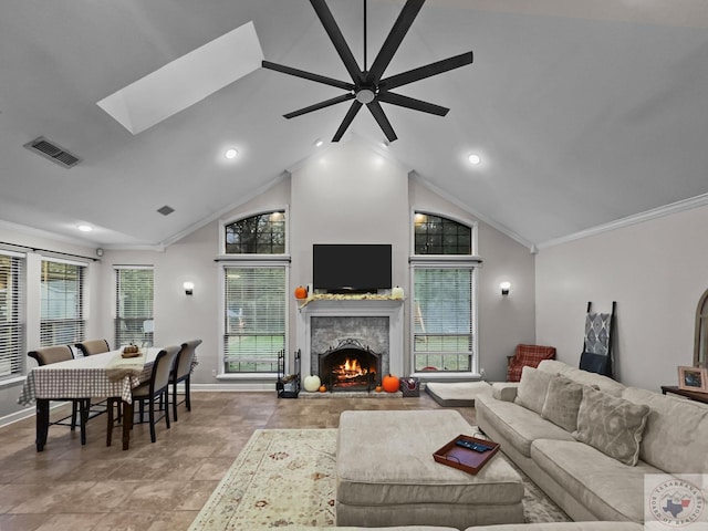 living room with a high end fireplace, a skylight, high vaulted ceiling, ornamental molding, and ceiling fan