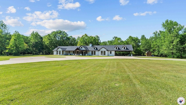 view of front of property with a chimney, a front lawn, a storage shed, and curved driveway