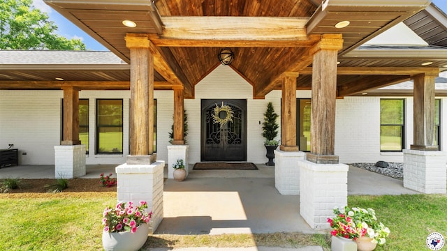 entrance to property featuring a porch and brick siding