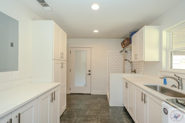 kitchen featuring a sink, electric panel, range, white cabinetry, and visible vents