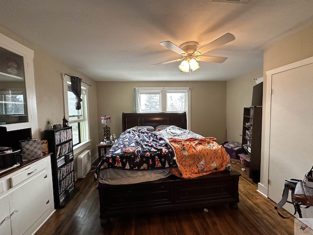 bedroom featuring ceiling fan, dark wood-type flooring, a textured ceiling, and radiator