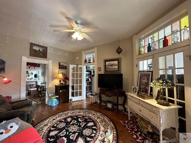 living room featuring ceiling fan, dark wood-type flooring, a textured ceiling, and french doors