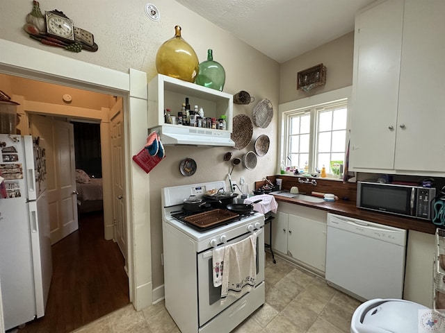 kitchen featuring white cabinets, white appliances, and a textured ceiling