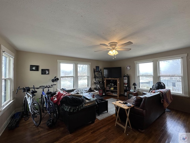 living room with a textured ceiling, ceiling fan, and dark hardwood / wood-style flooring