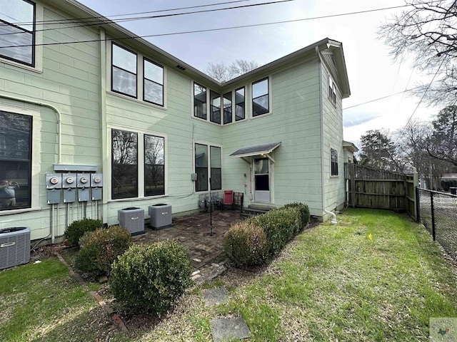 rear view of house with a yard and central AC