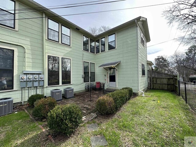 rear view of house with a yard and central AC