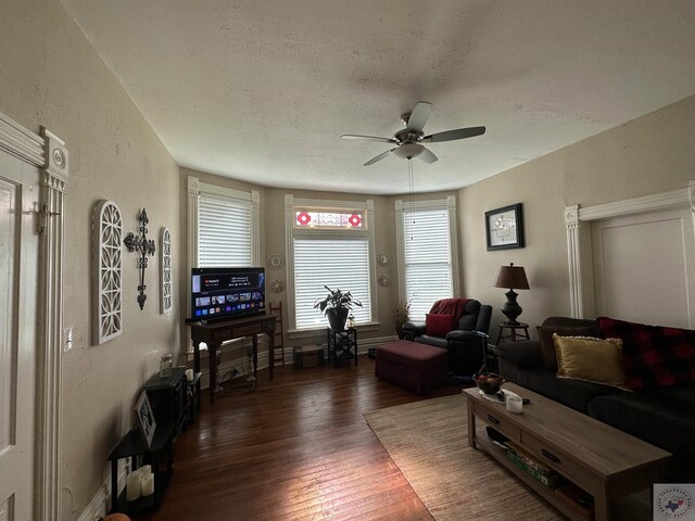 living room with dark wood-type flooring, a textured ceiling, and ceiling fan