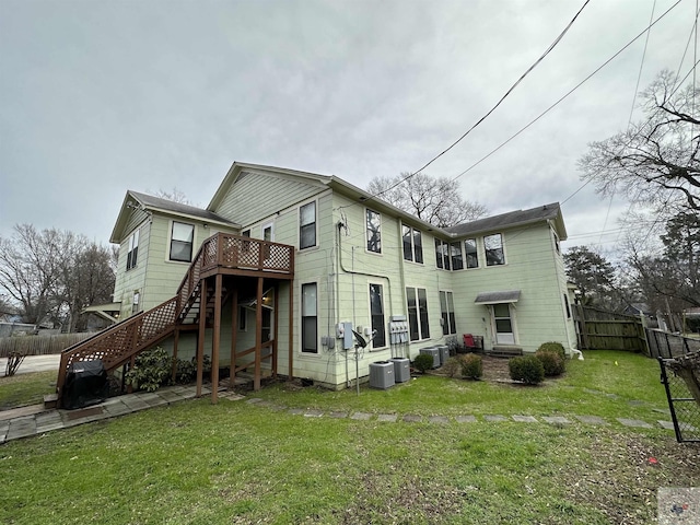 rear view of property with a deck, central air condition unit, and a yard